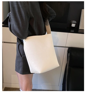 Weiße Beuteltasche aus Leder mit breitem Schultergurt getragen von einem Model
