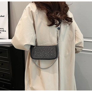 Detail of a chic black saddle bag with silver rhinestones and a metal chain strap