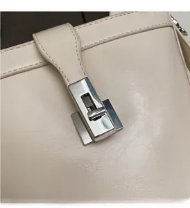 Dettaglio della chiusura a scatto in metallo argento su borsa a secchiello in pelle beige