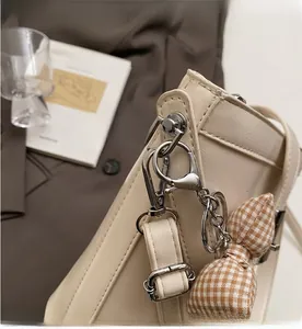 Dettaglio della ferramenta argento e fiocco a scacchi su una borsa a secchiello beige