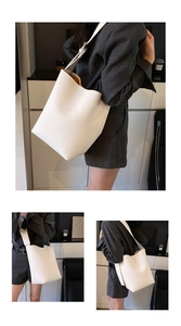 Makroansicht der cremeweißen Beuteltasche aus Leder mit Narbung und breitem Gurt