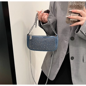 Detail of blue denim shoulder bag featuring sparkling silver rhinestones and chain strap