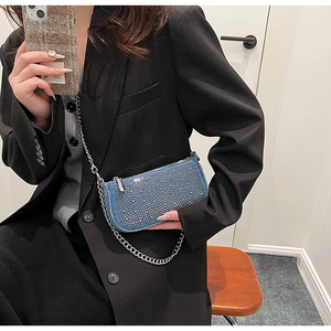 Detail of blue denim crossbody bag with sparkling rhinestones and silver chain strap