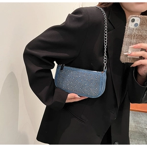 Close-up of denim baguette bag with silver rhinestones and chunky metal chain strap