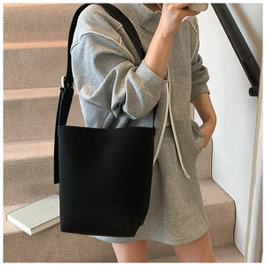 Detail einer minimalistischen schwarzen Eimertasche mit breitem Riemen an einem Model