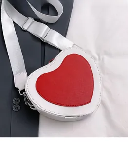 Detail of white heart-shaped crossbody bag with red patch and wide strap