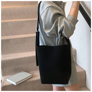 Minimalistische schwarze Canvas-Beuteltasche in der Seitenansicht an einem Model getragen