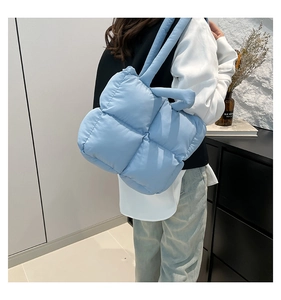 Detaillierte Seitenansicht der blauen gesteppten Puffer-Tasche getragen von einem Model
