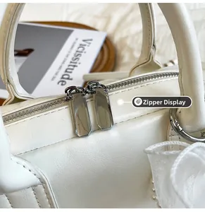 Vue détaillée de la double fermeture éclair en métal sur un sac Boston blanc vintage