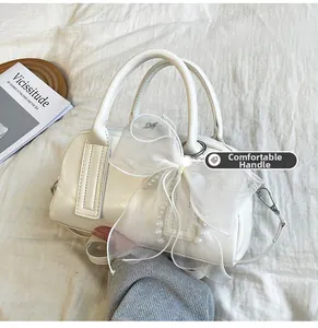 Détail d'un sac Boston blanc avec nœud en organza et perles sur un tissu blanc