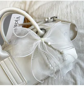 Gros plan détaillé d'un sac blanc en cuir avec un grand nœud en organza perlé