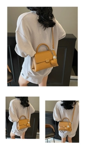 Detailed view of mustard yellow pebbled leather handbag with heart charm and shoulder strap