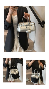 Detail of silver metallic bucket bag with pearl chain strap and heart charm pendant