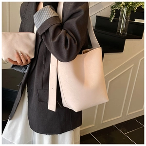 Nahaufnahme der beigen Lederbeuteltasche mit kleinem Etui an einem Model im Treppenhaus