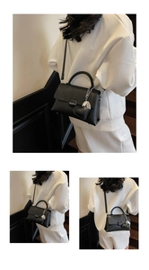 Detail of black lychee leather handbag with heart chain charm and metal buckle