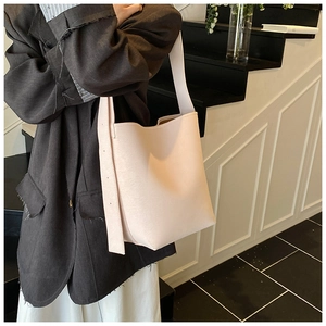 Nahaufnahme der rosa Beuteltasche mit breitem Gurt an einem dunklen Blazer