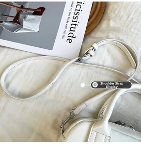 Détail de la bandoulière réglable et amovible avec boucle argentée sur un sac blanc