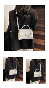 Detail of white lychee pattern leather handbag with heart charm on a dark staircase