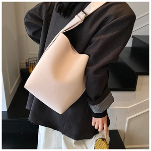 Détail d'un grand sac seau beige avec bandoulière large et boucle dorée