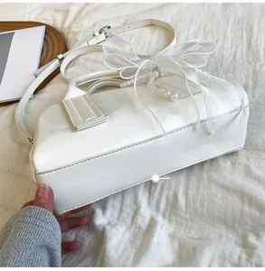 Détail d'un sac Boston blanc en similicuir avec perles et un nœud décoratif en résille