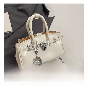 Close-up of white leather bucket bag with silver hardware and heart-shaped pendant
