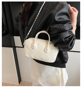 Detail of cream white leather bowling bag with silver chain strap and embossed logo