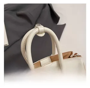 Detail of cream white handbag featuring silver metal hardware and double leather handles