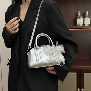 Détail du sac argenté métallisé avec nœud en dentelle de perles et bandoulière chaîne