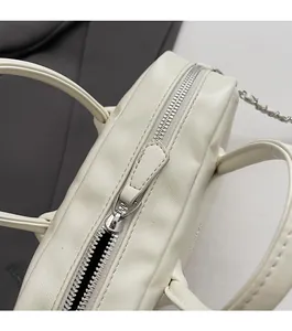 Detailed macro view of the smooth silver zipper and stitching on the cream bowling bag