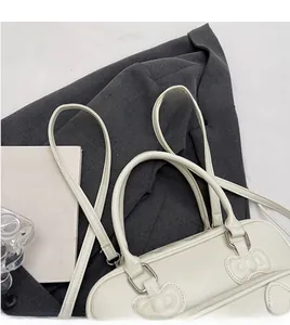 Detail view of the beige PU leather handbag with embossed bow and adjustable shoulder strap