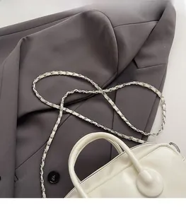 Detail of white leather bowling bag showing rounded top handles and silver chain strap
