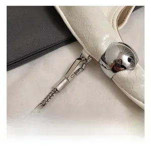 Close-up of silver metal ball hook and cracked white leather texture on a fashion handbag