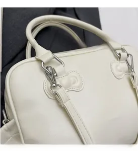Detailed close-up of premium silver-tone hardware on a cream-white Boston handbag
