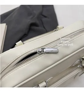 Detail of smooth silver zipper closure on textured white leather Boston bag