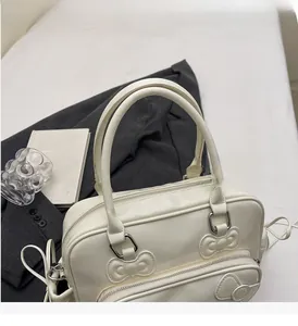 Detail view of cream white PU leather tote bag with elegant bow relief and sturdy handle