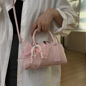 Détail du mini sac Boston rose avec grand nœud en voile et breloques en perles