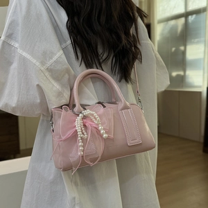 Détail du sac en cuir verni rose avec nœuds en résille et glands en perles chic