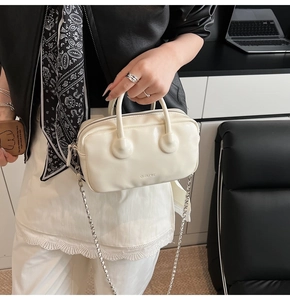 Detail showing cream bowling bag with CLEAUN logo and woven chain strap on a model