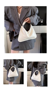 Close-up of white triangular pleated handbag with silver metallic sphere and chain strap