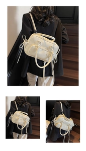 Detail of cream white leather Boston bag showing bow tie accents and versatile straps