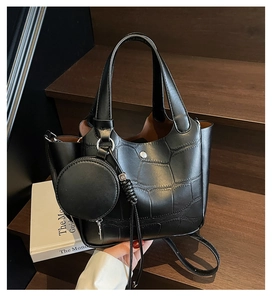 Détail du sac seau noir à motif crocodile avec boucle en métal et mini porte-monnaie suspendu