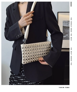Detail of cream crossbody bag featuring silver rivet studs and industrial rock style