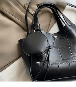 Détail d'un sac seau noir motif crocodile avec son porte-monnaie rond sur un blazer