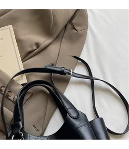 Détail de la bandoulière en cuir noir avec boucle métallique argentée réglable sur le sac