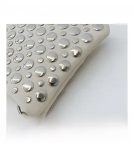 Close-up of beige PU leather handbag with silver stud embellishments and metal hook