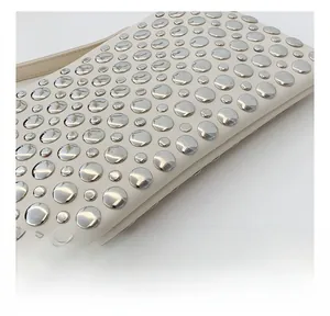 Detailed close-up of silver metal rivets and precision stitching on the cream leather bag