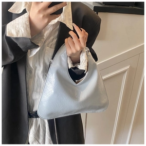 Detail of light blue triangular handbag with glossy wrinkled leather and silver chain