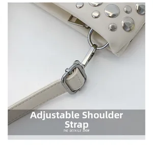 Detail of adjustable silver buckle and stud hardware on beige punk style shoulder bag