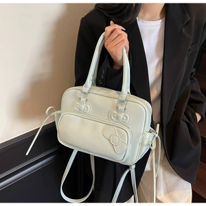 Detail of mint green crossbody bag with decorative bows and adjustable shoulder strap
