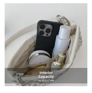 Internal capacity of white studded punk bag showing phone and cosmetics layout